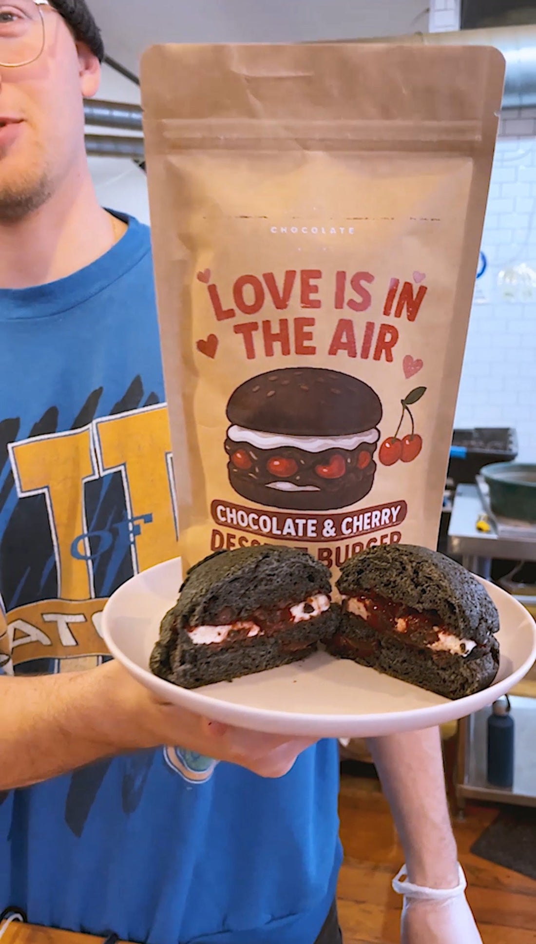 Person holding a plate of dark chocolate cookies with a package labeled &